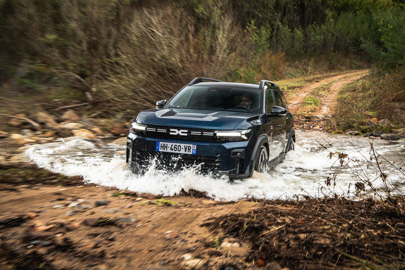 Dacia Bigster Hybrid 4x4 bei der Bachquerung im Offroad-Einsatz, Frontansicht mit Wasserspritzern