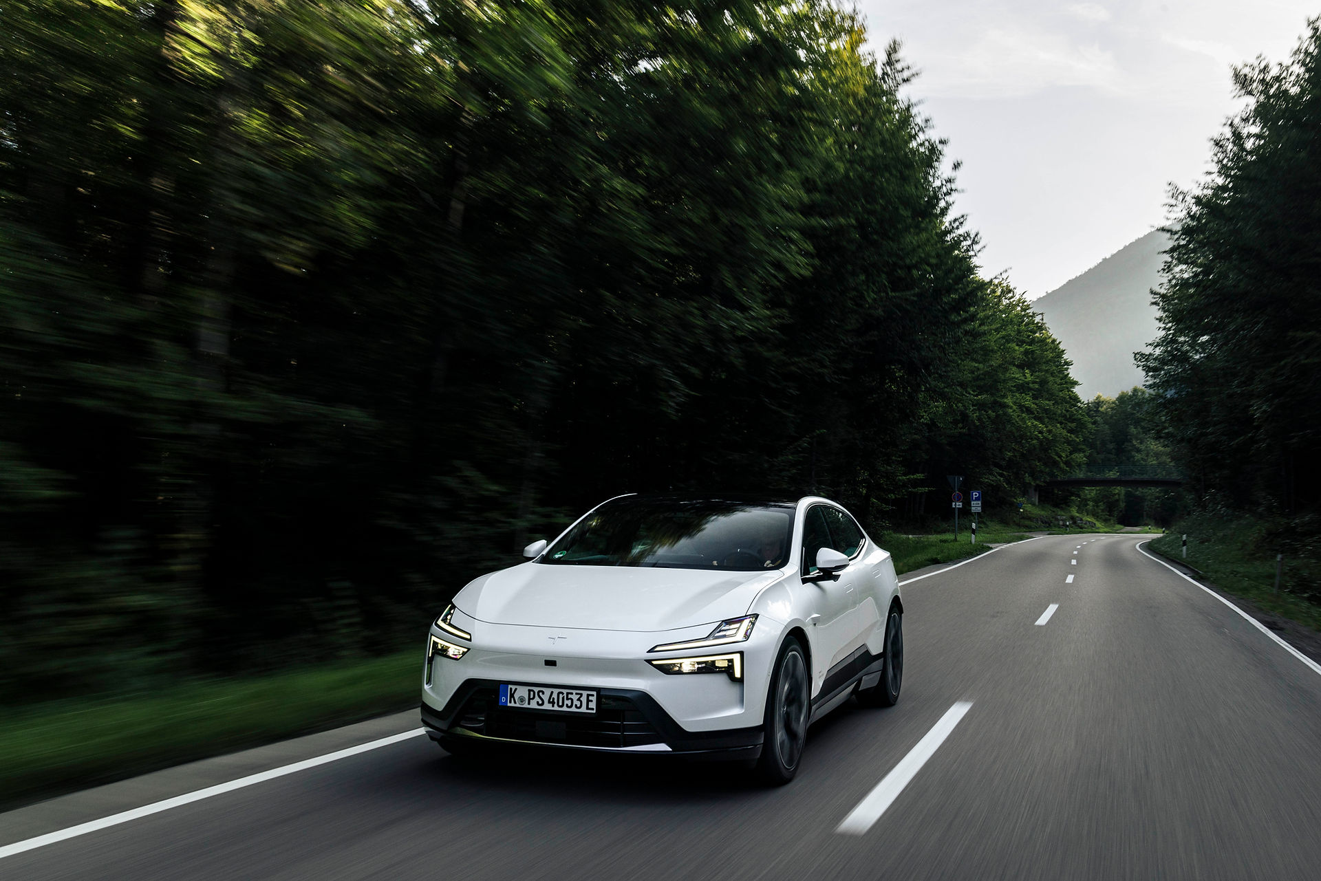 Polestar 4 mit markantem LED-Lichtdesign und aerodynamischer Front, unterwegs durch den Wald.