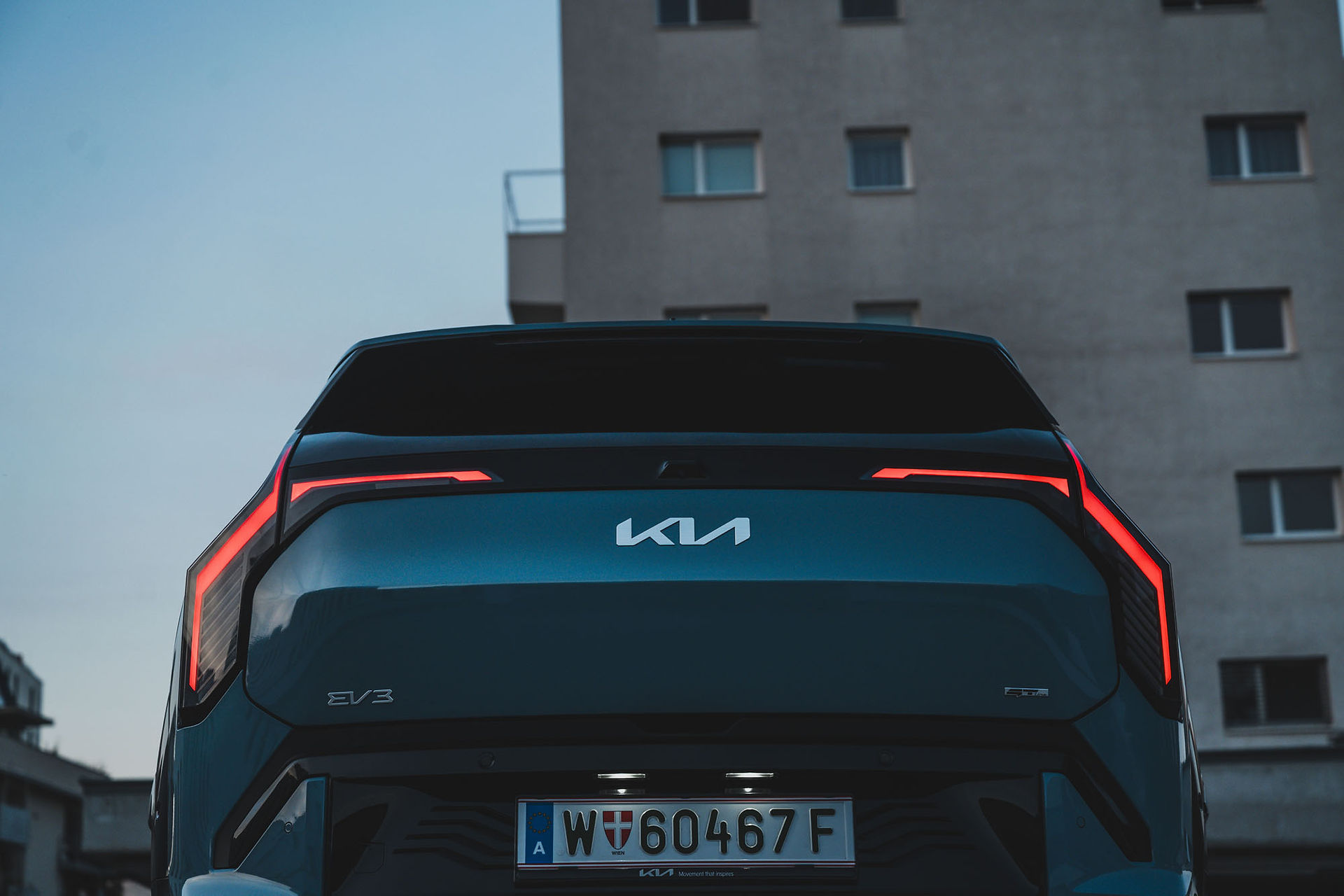 Kia EV3 Heckansicht bei Dämmerung – LED-Rückleuchten mit „Star Map“ Lichtsignatur, Dachkantenspoiler, GT-Line Design