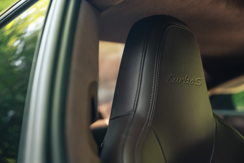 Brauner Clubleder Sportsitz des Porsche 911 Turbo S 992.1 mit eingeprägtem Turbo S Logo in der Kopfstütze.