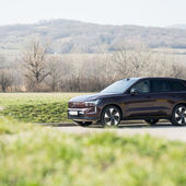Volvo EX90 Ultra Twin Motor 2026 in dunklem Rotbraun in Seitenansicht, fotografiert vor sanften Hügeln und winterkahlen Weinbergen am Stadtrand von Wien