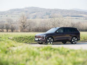 Volvo EX90 Ultra Twin Motor 2026 in dunklem Rotbraun in Seitenansicht, fotografiert vor sanften Hügeln und winterkahlen Weinbergen am Stadtrand von Wien