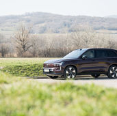 Volvo EX90 Ultra Twin Motor 2026 in dunklem Rotbraun in Seitenansicht, fotografiert vor sanften Hügeln und winterkahlen Weinbergen am Stadtrand von Wien