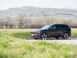 Volvo EX90 Ultra Twin Motor 2026 in dunklem Rotbraun in Seitenansicht, fotografiert vor sanften Hügeln und winterkahlen Weinbergen am Stadtrand von Wien