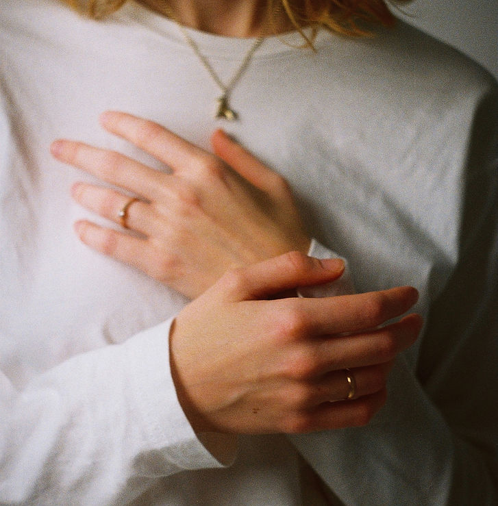 Close-up of woman resting hands on chest during somatic trauma therapy in Allen, TX.