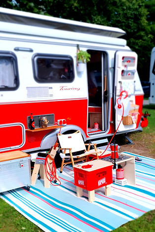 Eine Puppenstuben Küche aus zwei Bierkästen vor einem Wohnwagen