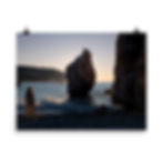 a woman gazing out at the sunrise over the water with a small sea stack rising up out of the water