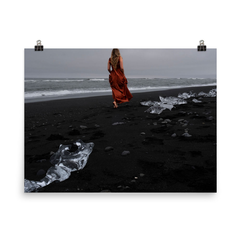 Woman in red walking along the Black Sand beach with glaciers washed ashore around her