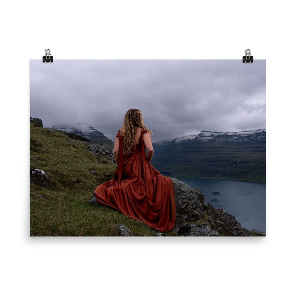 Woman in red sitting on a rock gazing out at rectangular cliffs in the background