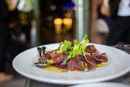 Carpaccio de viande séchée et salade sur une assiette blanche, accord mets et vins pour Distinction du Domaine de La Garnaudière