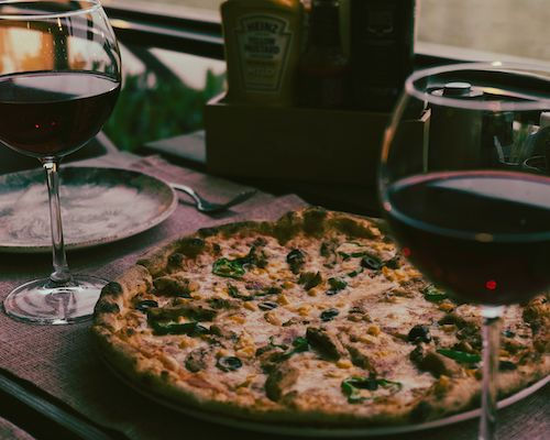 Pizza accompagnée de deux verres de vin rouge, accord mets et vins du Cabernet Sauvignon rouge du Domaine de La Garnaudière