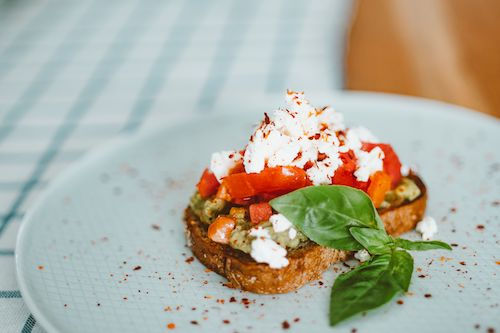 Bruschetta à la tomate et au fromage frais sur une assiette bleutée, accord fromage du cocktail Alizée bleue du Domaine de La Garnaudière