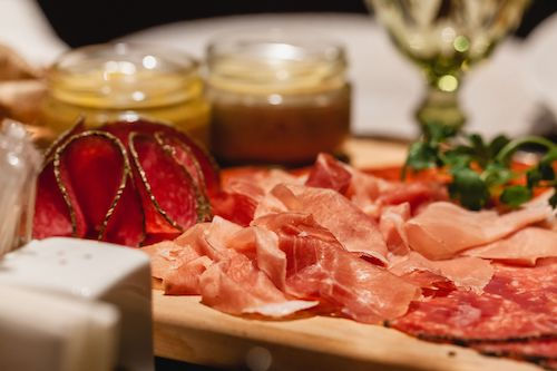 Jambon cru et charcuterie sur une planche avec des confitures, accord mets et vins pour le Gamay rosé du Domaine de La Garnaudière