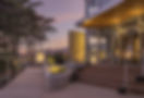 Entree principale hotel Punta Lara Noirmoutier au crepuscule terrasse bois clair bornes lumineuses borne pierre gravee accueil grandes baies vitrees plafond bois exotique reception enseigne lumineuse restaurant Atlantide pinede ciel degrade violet rose banc beton blanc vegetation mediterraneenne