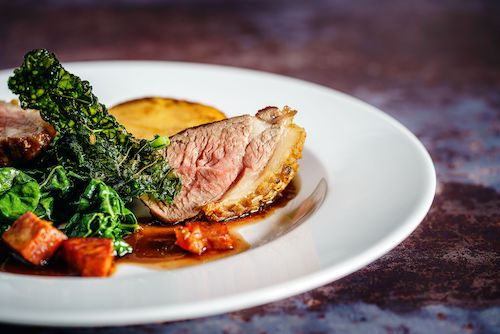 Tranches de viande rosée et choux kale sur une assiette blanche, accord mets et vins pour le Muscaris du Domaine de La Garnaudière