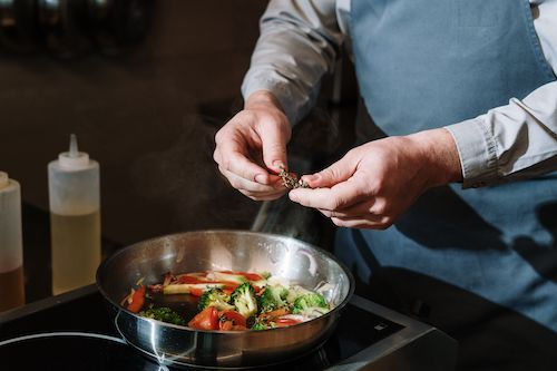 Cuisinier faisant sauter des légumes à la poêle, accord végétarien du Muscaris du Domaine de La Garnaudière
