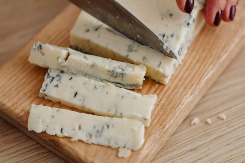 Fromage bleu coupé en tranches sur une planche, accord fromage de L'Élégance du Domaine de La Garnaudière