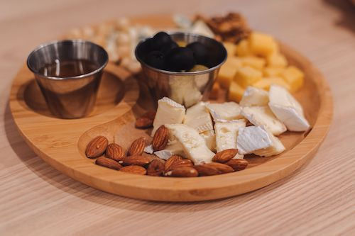 Plateau de fromages, amandes et fruits secs sur une planche ronde, accord fromage du Cabernet Sauvignon rouge du Domaine de La Garnaudière