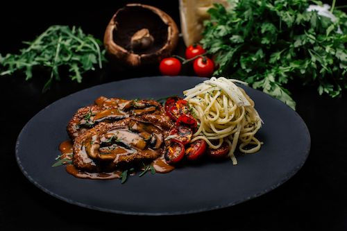 Escalopes aux champignons et spaghettis sur une assiette en ardoise, accord mets et vins pour le Gamay rouge du Domaine de La Garnaudière