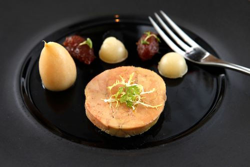 Foie gras aux poires pochées et aux figues sur une assiette noire, accord mets et vins pour L'Élégance du Domaine de La Garnaudière