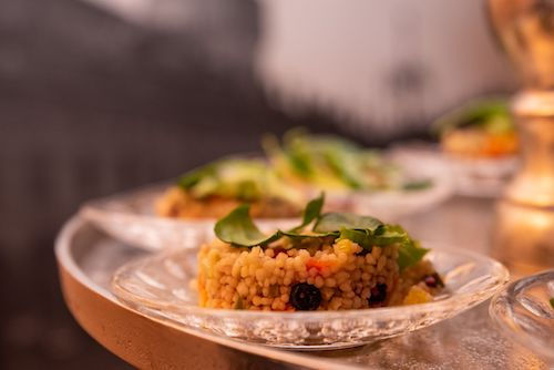 Semoule aux légumes et aux raisins secs servie sur une assiette en verre, accord végétarien du cocktail Cranberry du Domaine de La Garnaudière