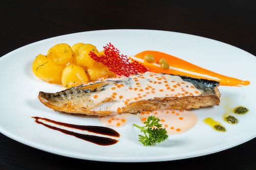 Filet de poisson aux pommes de terre rissolées et sauce rouge sur une assiette blanche, accord mets et vins pour le Pinot gris du Domaine de La Garnaudière