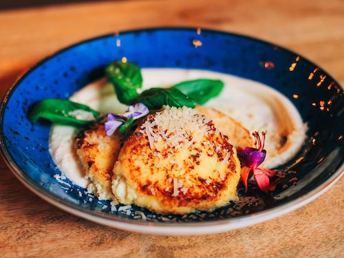 Galette de légumes gratinée sur une purée dans un bol bleu, accord fromage du Gamay rouge du Domaine de La Garnaudière