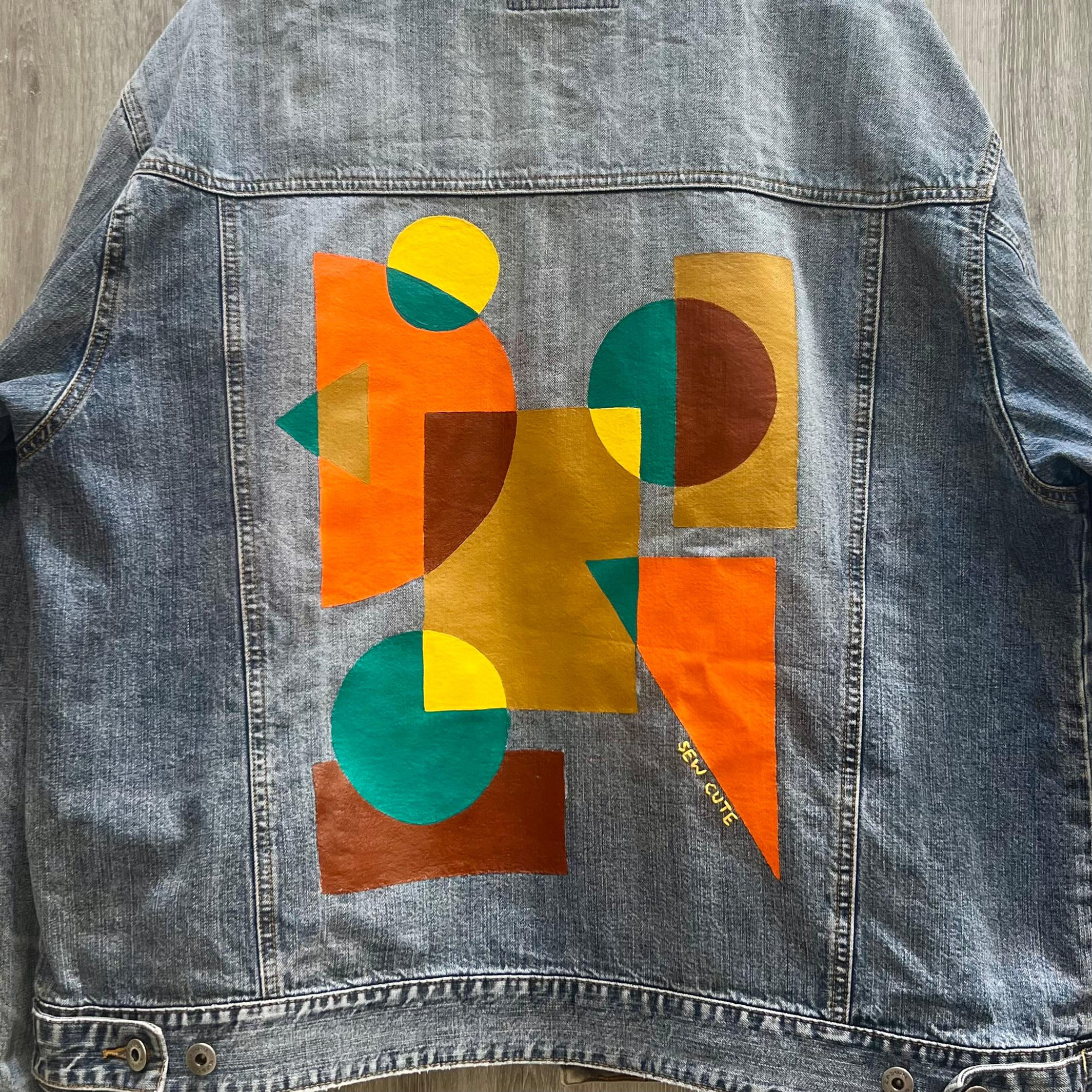 Colorful geometric abstract design painted on oversized light wash jean jacket