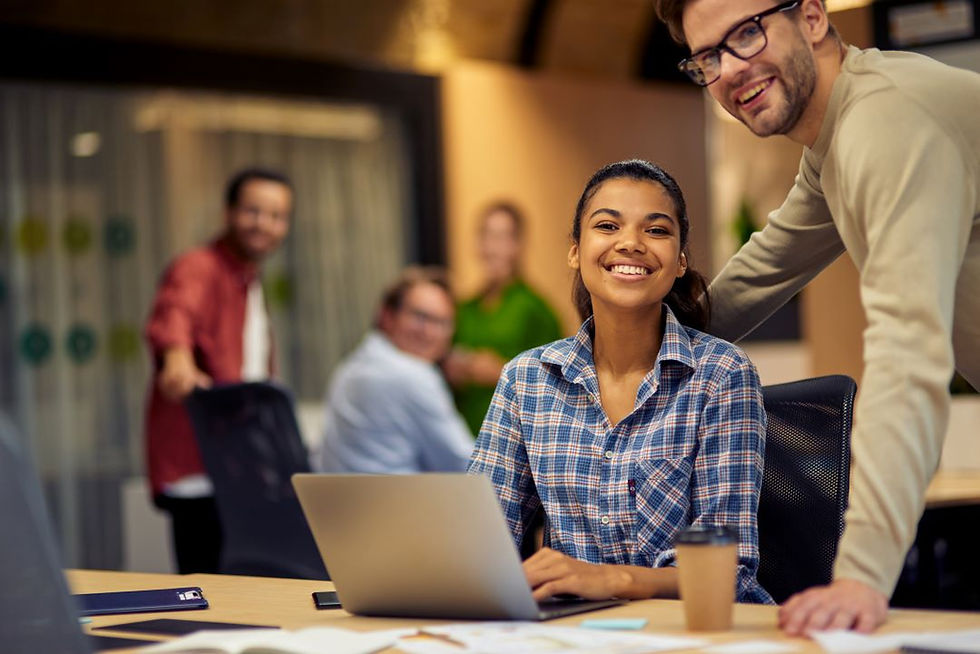 two-young-multiracial-colleagues-looking-camera-smiling-while-working-together-laptop