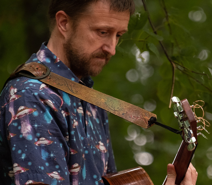 Matt Kik playing his acoustic guitar in the woods.