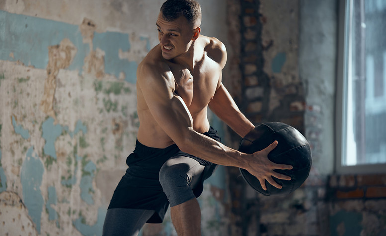 Full body workout. Young muscular man with strong, relief body shape training shirtless wi