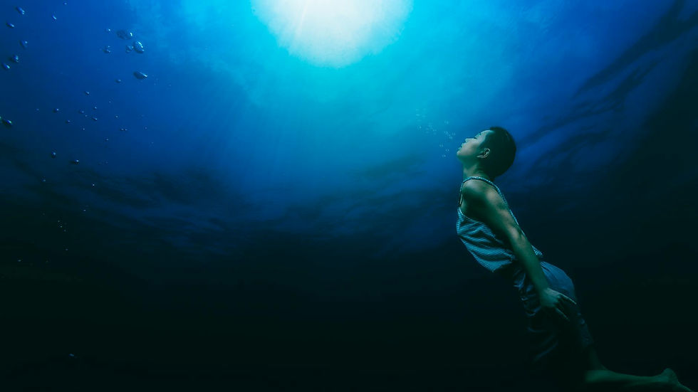 A serene scene of a person swimming underwater towards sunlight, capturing tranquility and exploration.