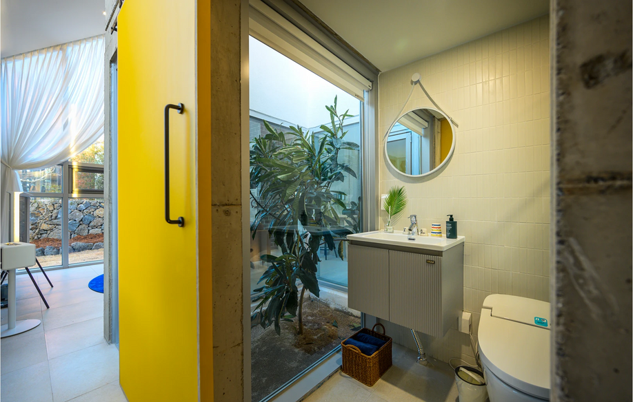 노란 문과 원형 거울이 있는 아담스테이 욕실, 감각적인 인테리어