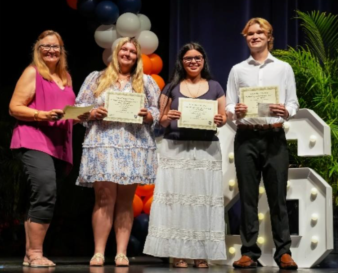Four high school seniors standing and smiling with scholarship certificates