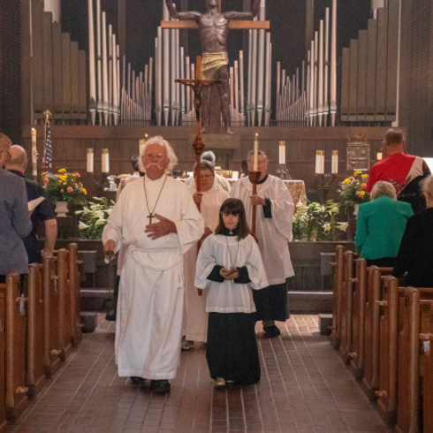 adults and child dressed as altar servers processing down the church aisle