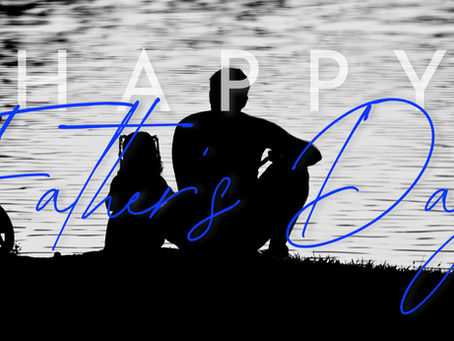 silhouette of father and child seated at the lake