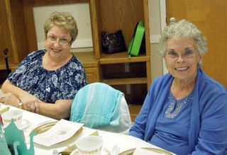 Two women sitting at a table smiling.