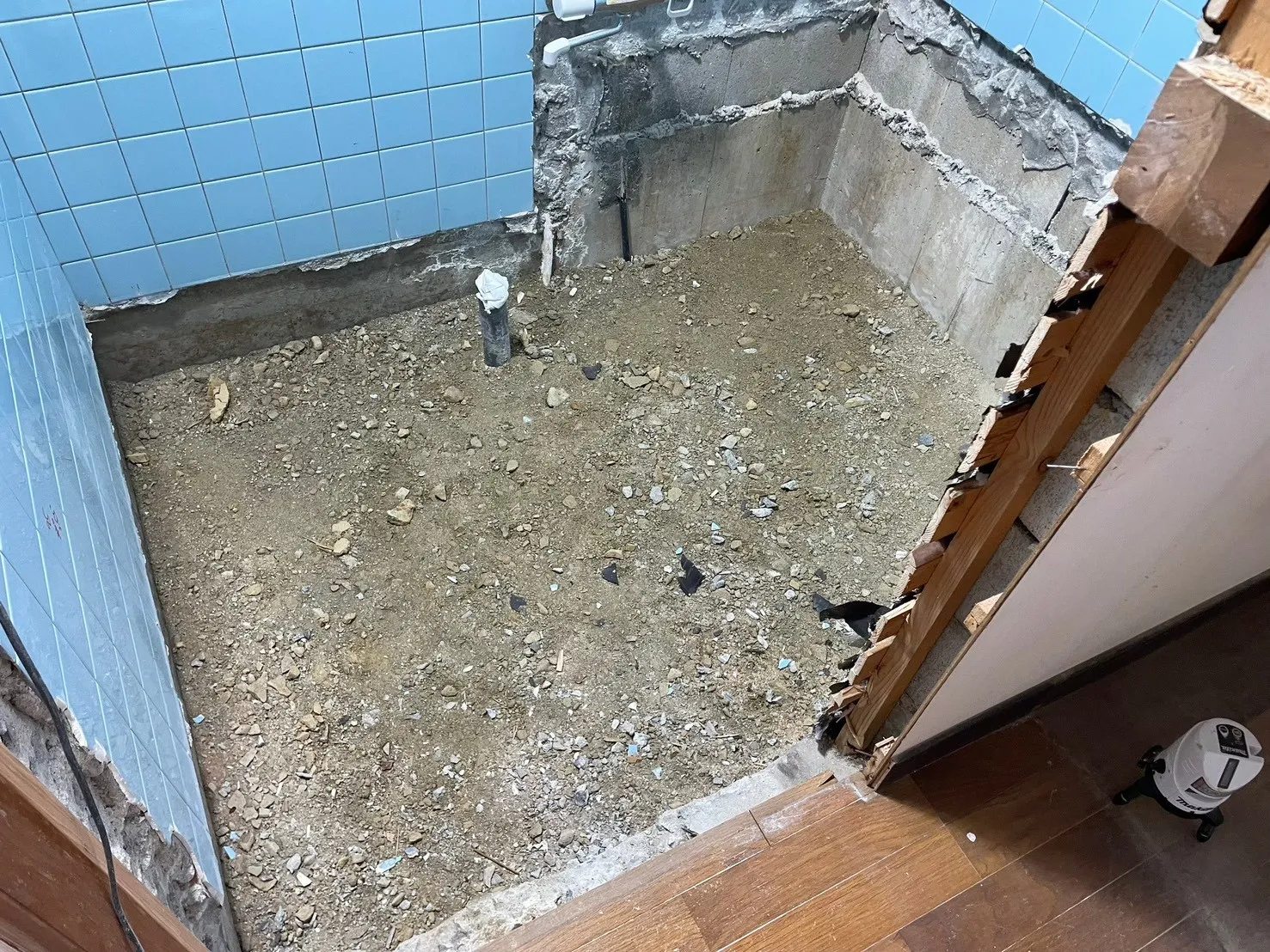 浴室の浴槽・床・タイルをすべて撤去した状態。土間が露出し、配管のみが残る解体直後の様子