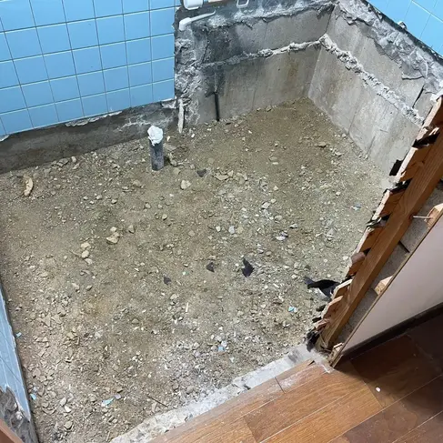浴室の浴槽・床・タイルをすべて撤去した状態。土間が露出し、配管のみが残る解体直後の様子