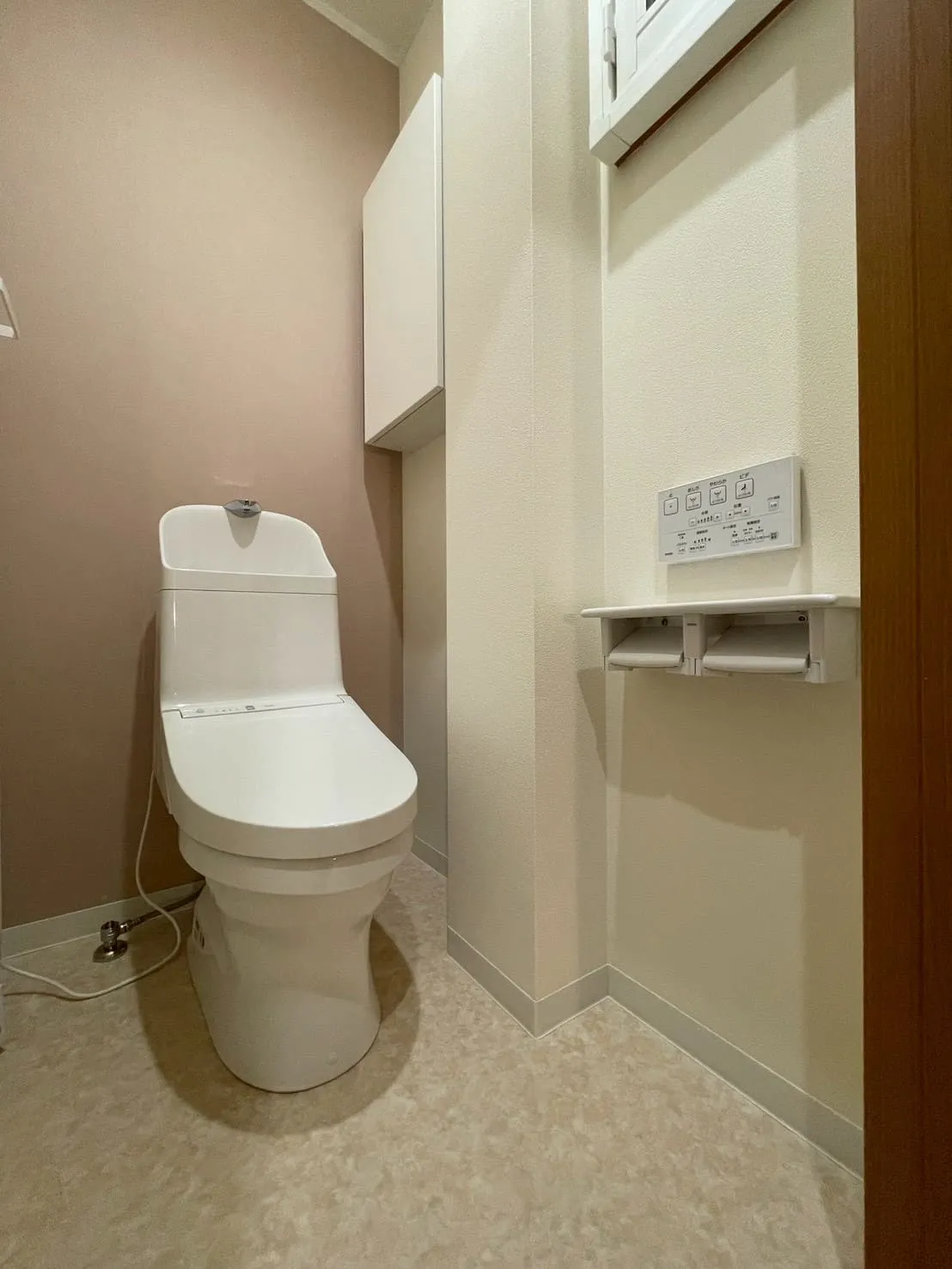 ピンクの壁と白いトイレ、収納棚を備えた完成後のトイレ空間