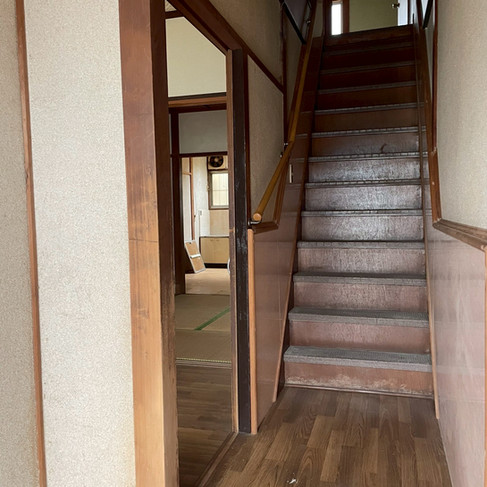 リノベーション前の室内階段。傷みの目立つ踏み板と急勾配の階段が残る施工前の状態
