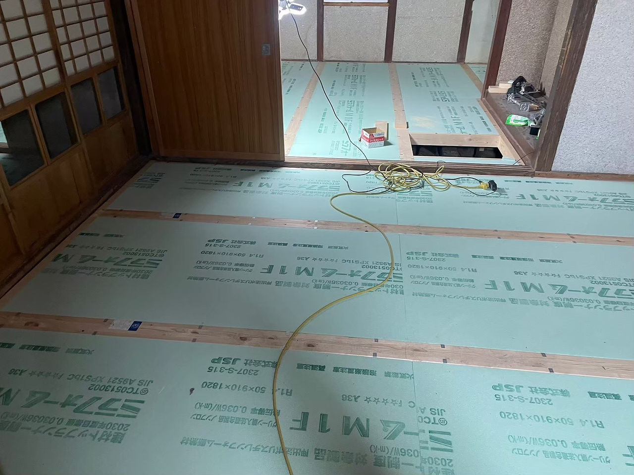 和室の床を捲り、根太の間にグリーンのスタイロフォーム断熱材を敷き詰めた施工中の様子