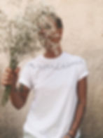 femme portant un t-shirt blanc brodé et un bouquet de fleurs