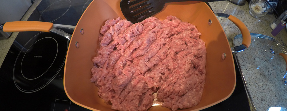 Breaking up ground pork in a frying pan using a spatula