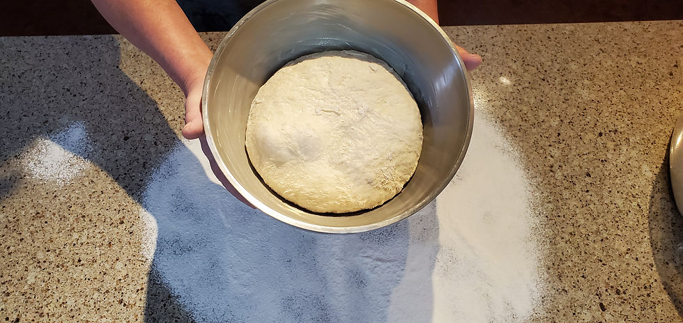 Risen dough in a stainless steel bowl.