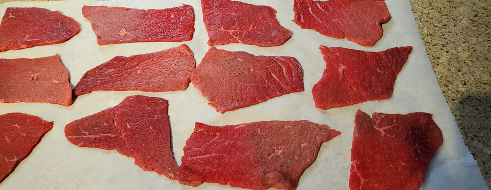 Flat pieces of beef on a parchment paper
