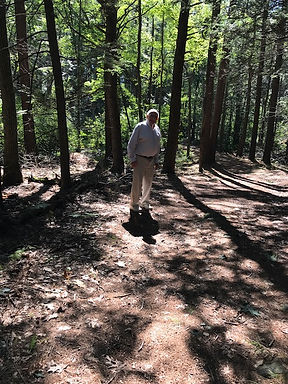 Man standing on woods trail in dappled sunlight