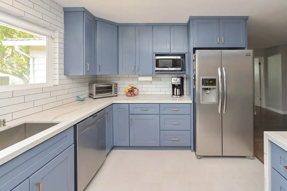 Modern kitchen with blue shaker cabinets, subway tile backsplash, white countertops, and stainless steel appliances – Green Bay Remodeling