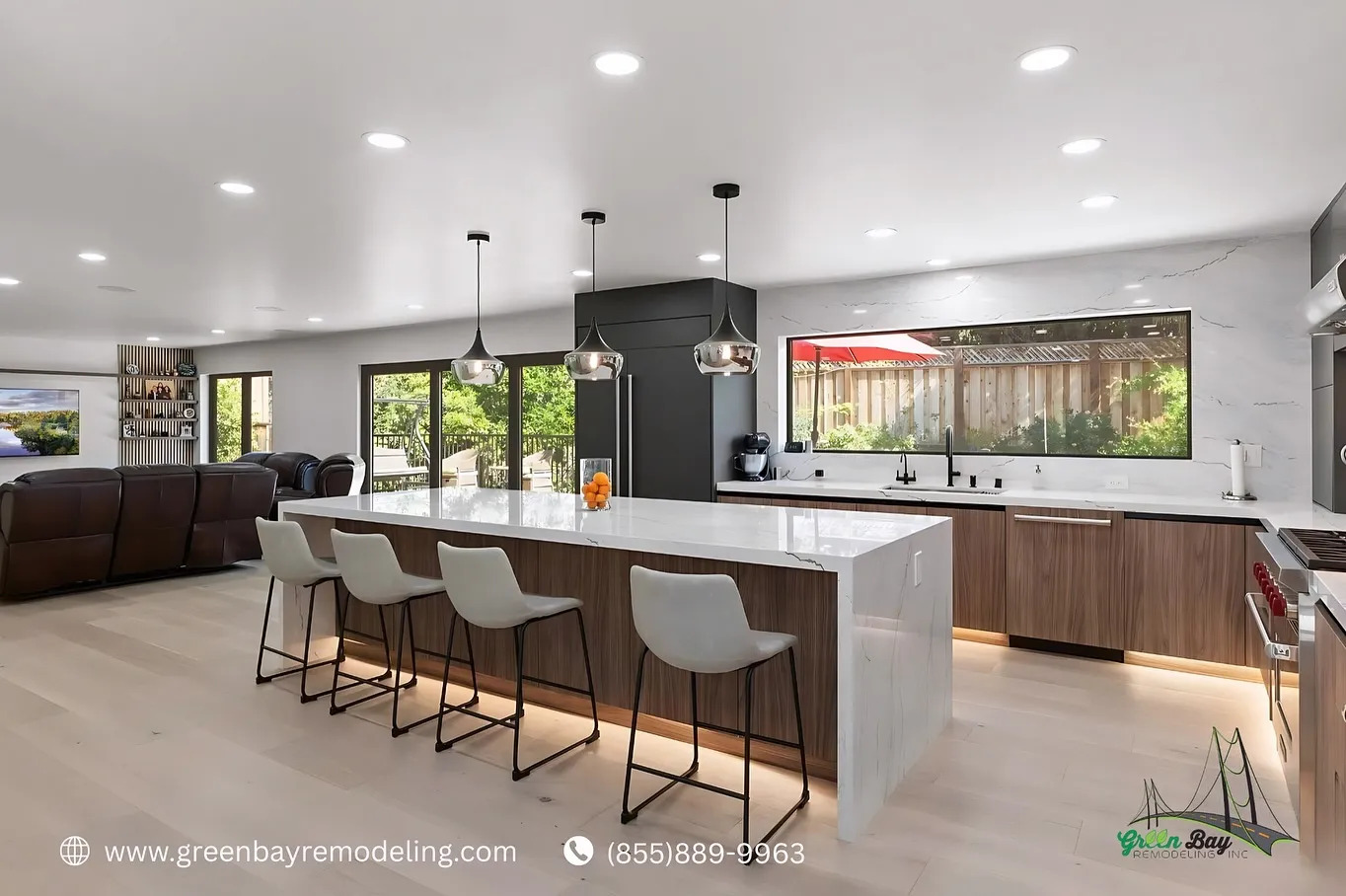 Modern open-concept kitchen with a large white waterfall island, pendant lighting, wood cabinetry, and seamless flow into the living area.