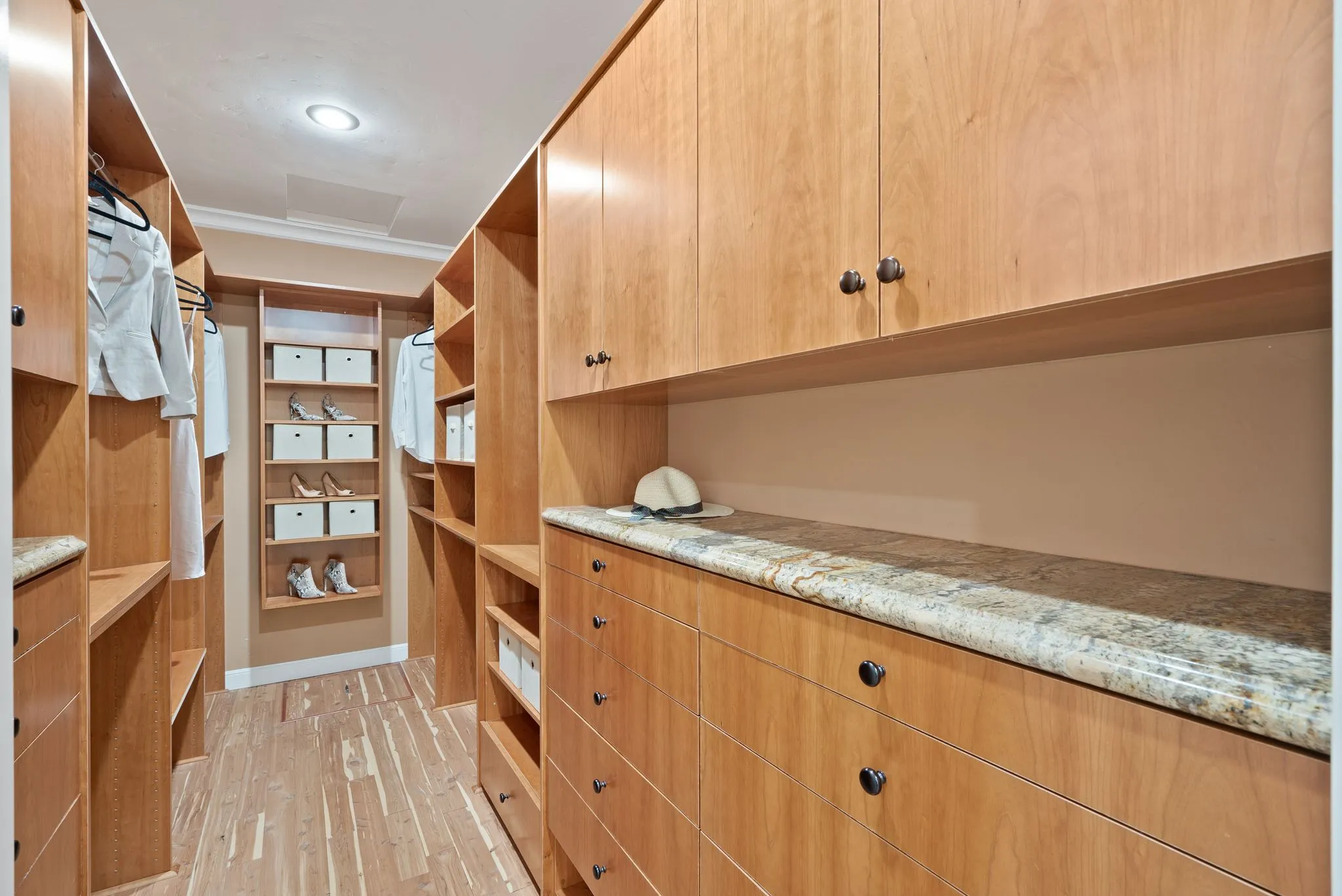 Spacious walk-in closet remodel featuring wood cabinetry and granite countertop.